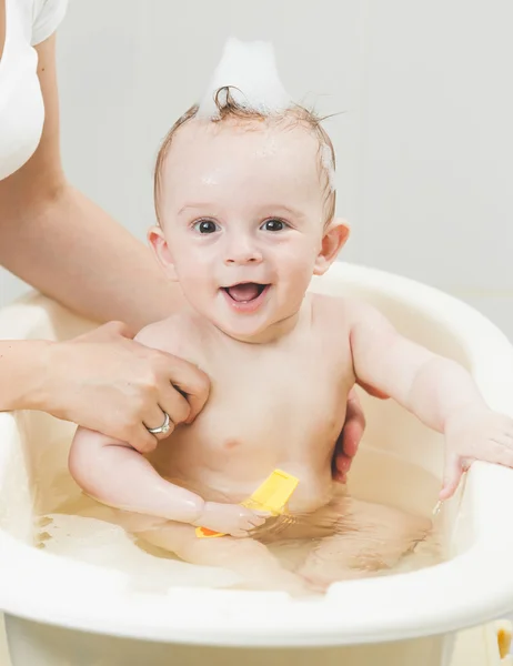Cheerful smiling baby boy having bath with foam Stock Picture