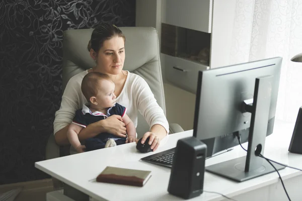 Красива мати сидить зі своїм маленьким сином на офісному стільці і — стокове фото