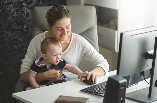 Kvinnan arbetar hemma kontoret och tar hand om hennes baby son — Stockfoto