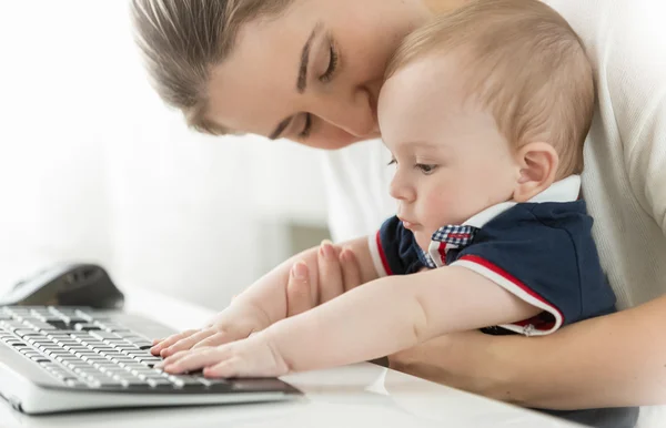 Närbild av söt baby sitter i mödrar knä och skriver på Tange — Stockfoto