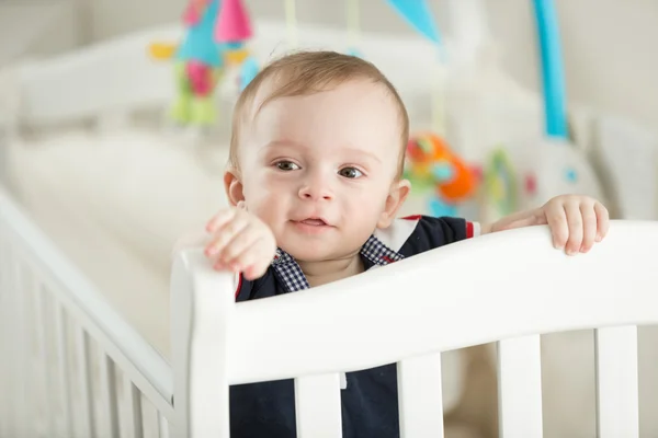 9-miesięcznego chłopca ząbkowanie i pozowanie w biała kołyska — Zdjęcie stockowe