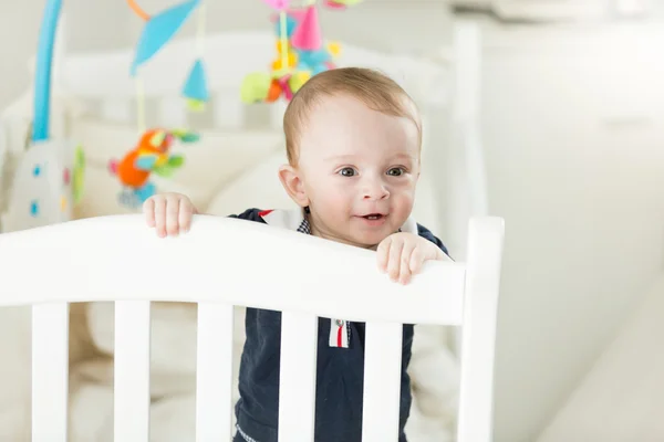 Toddler chłopiec stoi w łóżku i opierając się na ogrodzenie — Zdjęcie stockowe