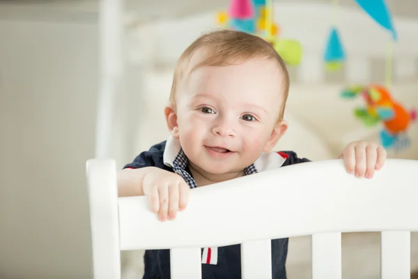 Schattige lachende babyjongen permanent zijn bed — Stockfoto