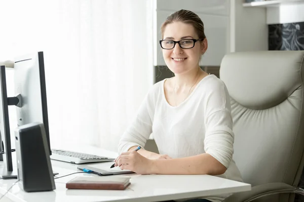 Sonriente diseñadora femenina trabajando en la oficina con una tableta gráfica y — Foto de Stock