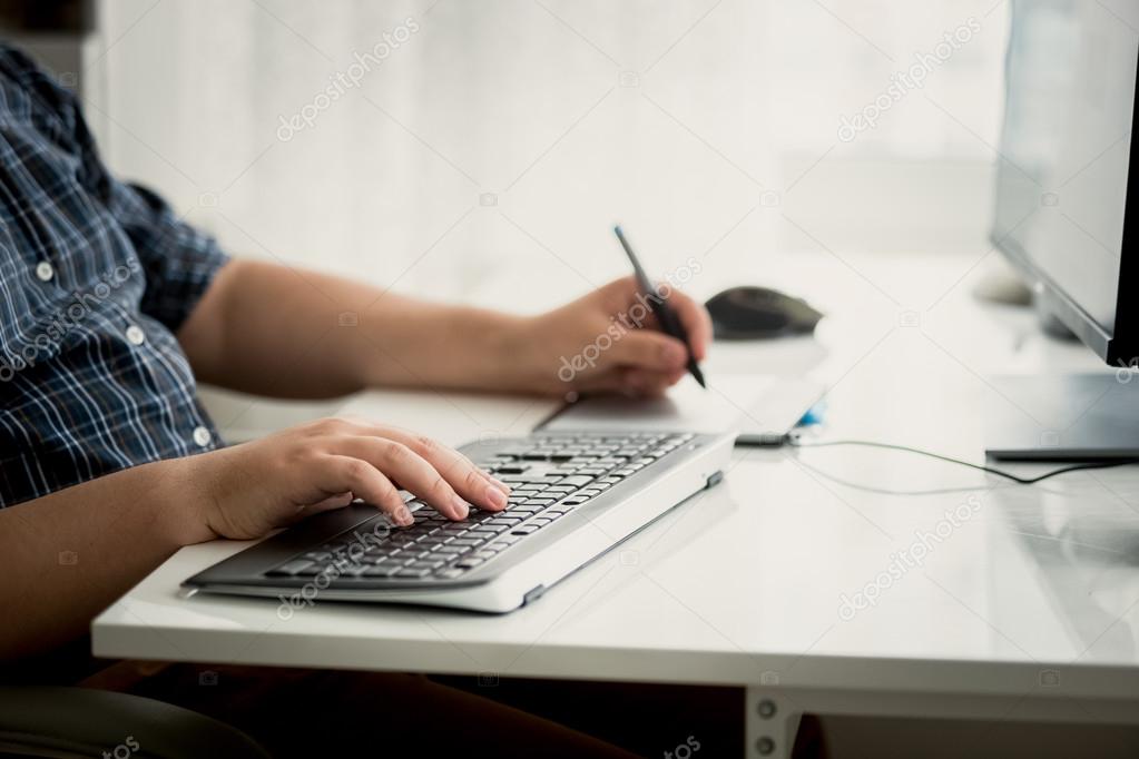 Toned photo of graphic designer using tablet and keyboard at wor
