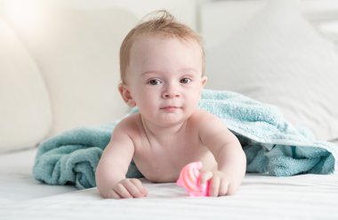 Yatakta mavi havlu altında yalan ve plastik tutarak bebek 