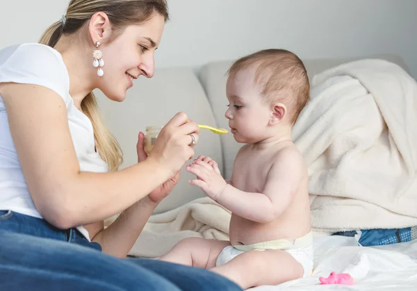 Счастливая молодая мать кормит своего ребенка ложкой — стоковое фото