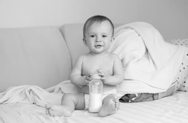 Fekete-fehér fotó kisfiú ül a tej bottl ágy — Stock Fotó