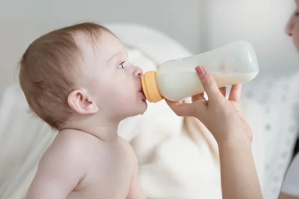 Retrato del niño sentado en la cama y comiendo leche del biberón — Foto de Stock