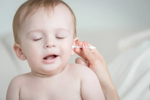 Primer plano de las madres limpiando la oreja de su bebé con un hisopo de algodón — Foto de Stock