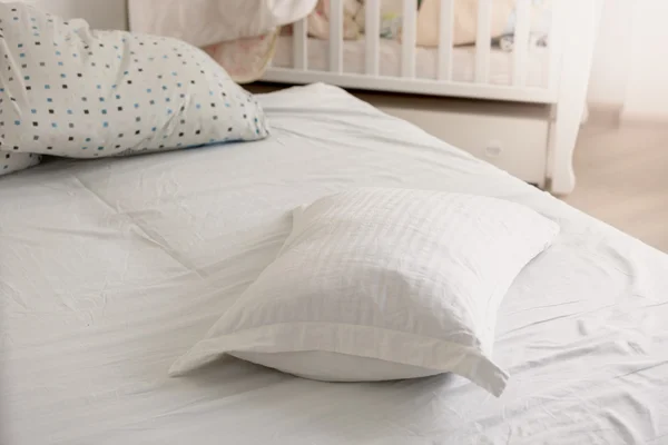 Closeup of white pillow on untidy bed at sunny day — Stock Photo, Image