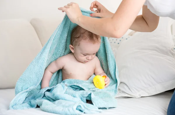 Matka znalazła swoje dziecko pod niebieski ręcznik, grając z gumy żółty — Zdjęcie stockowe