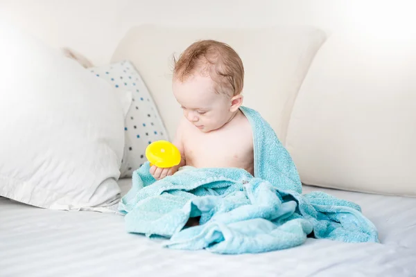 Bébé garçon couvert de serviette bleue jouant avec canard en caoutchouc jaune o — Photo