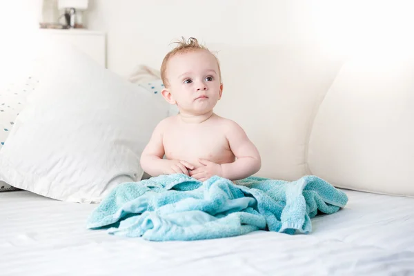 Bebê recém-banhado coberto de toalha azul sentado no sofá grande em — Fotografia de Stock