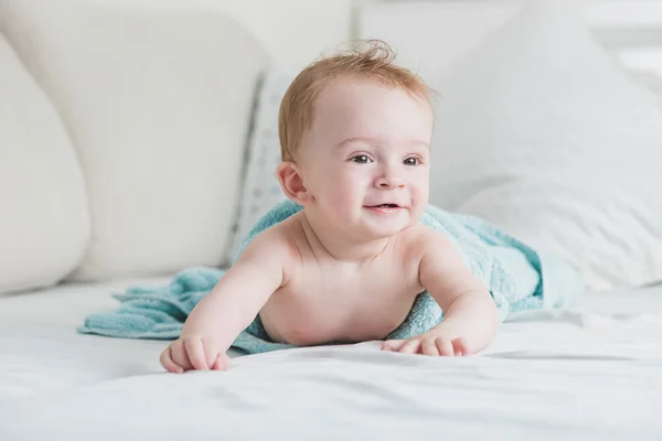 Adorable bébé souriant en serviette bleue après la douche rampant sur le lit — Photo