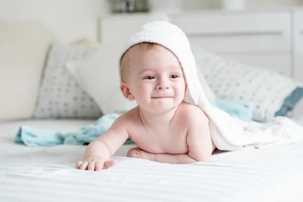 Bébé garçon souriant en serviette à capuchon rampant sur le lit après avoir ba — Photo