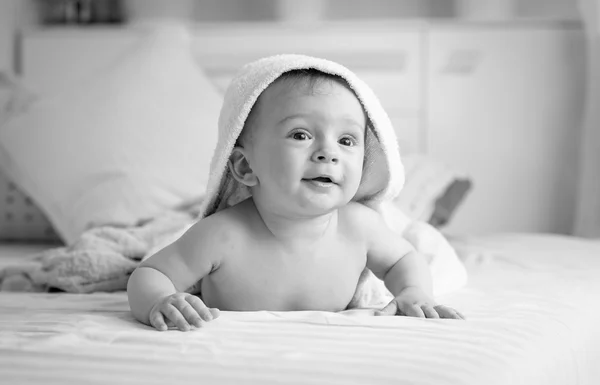 黑色和白色的开朗婴儿在床上蒙面毛巾的肖像 — 图库照片