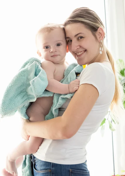 Retrato tonificado de madre feliz abrazando a su bebé niño cubierto en b — Foto de Stock