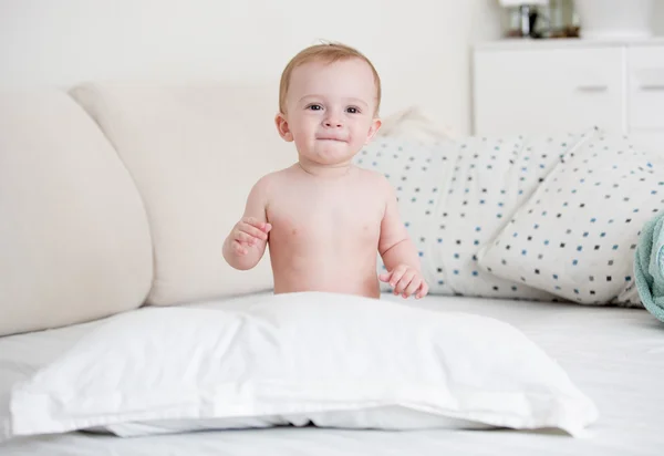 Naken pojke sitter på sängen i sovrummet — Stockfoto