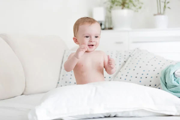 Veselá nahý chlapeček hraje na posteli s polštáři — Stock fotografie