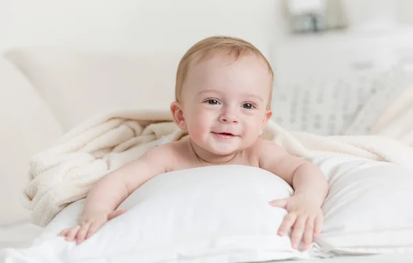 Alegre sorrindo bebê menino deitado em grande cama — Fotografia de Stock