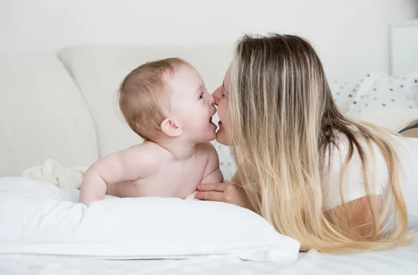 Retrato de bebé alegre con madre acostada sobre una gran almohada blanca — Foto de Stock