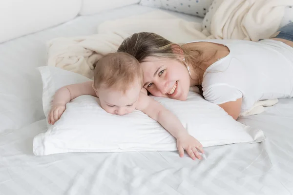 Portrait of happy mother lying on big pillow with her 9 months o — Stock Photo, Image