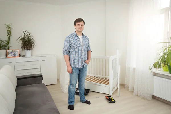 Knappe man permanent bij gedemonteerde babywieg op slaapkamer — Stockfoto