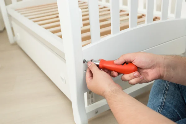 Close-up van klusjesman aanscherping van de schroeven op wit houten bed — Stockfoto