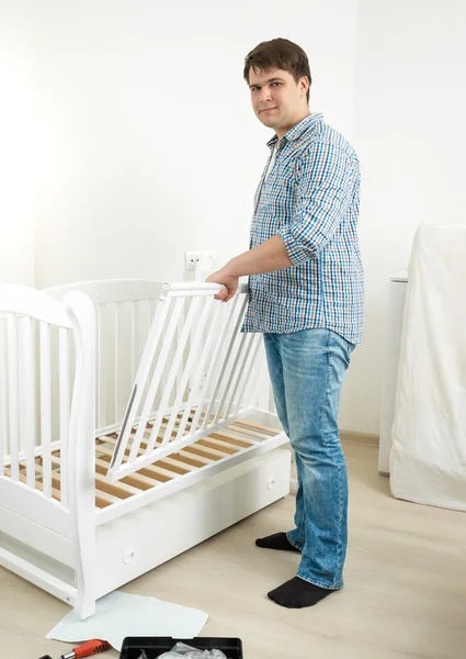 Young man assembling furniture in baby's room — Stock Photo, Image