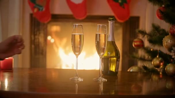 Primer plano del hombre y la mujer sentados en la chimenea y beber champán en la víspera de Navidad — Vídeos de Stock