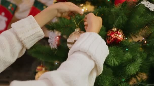 Primer plano de niña decorando el árbol de Navidad. Cámara se acerca de las manos a bauble — Vídeos de Stock