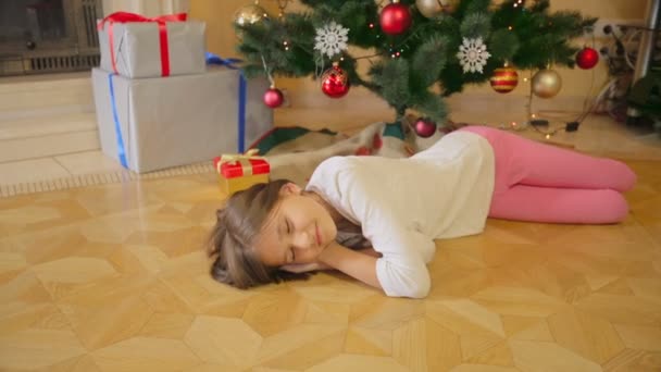 10 歳の女の子朝のクリスマス ツリーの下に眠っています。階に存在を残して母. — ストック動画