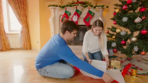 Feliz jovem casal embrulhando presentes de Natal e beijando — Vídeo de Stock