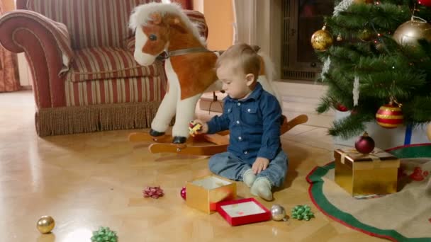 Niedlicher kleiner Junge spielt mit Spielzeug auf dem Boden unter dem Weihnachtsbaum — Stockvideo