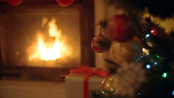 Κοντινό πλάνο εικόνα του χρυσά και κόκκινα στολίδια στο χριστουγεννιάτικο δέντρο. Τζάκι στο φόντο. — Αρχείο Βίντεο