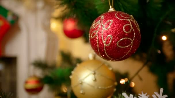 Closeup de bugigangas douradas e vermelhas penduradas na árvore de Natal na sala de estar — Vídeo de Stock