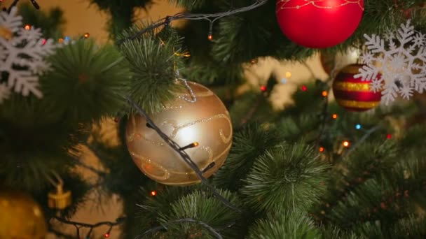 Closeup όμορφη χρυσή στολίδι στο χριστουγεννιάτικο δέντρο με λαμπερό φώτα πολύχρωμα — Αρχείο Βίντεο