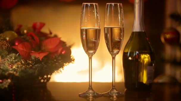 Primer plano de dos flautas de champán en la mesa de la cena en el cuarto oscuro con chimenea ardiente — Vídeos de Stock