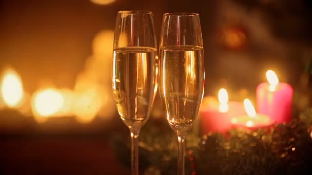 Two glasses of champagne on table in front of burning fireplace at Christmas eve. — Stock Video