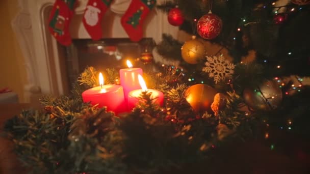 Dolly coup de couronne de Noël avec des bougies rouges brûlantes sur la table au salon — Video