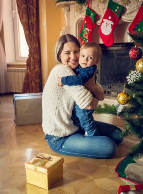 Mutlu genç anne onun 1 yaşındaki bebek çocuk Noel'de sarılma 
