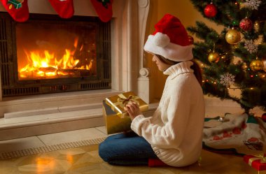 Noel hediye kutusu, şömine ile oturup Noel Baba şapkalı kız bir