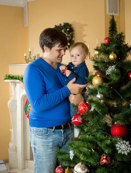 快乐的父亲抱着他的宝贝儿子，看着圣诞树 — 图库照片