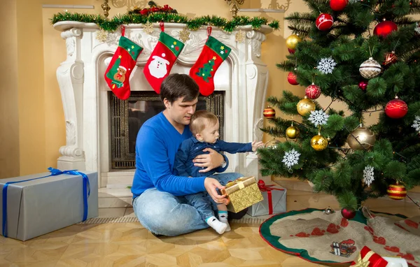 Счастливый отец играет со своим маленьким сыном на полу под Рождество — стоковое фото
