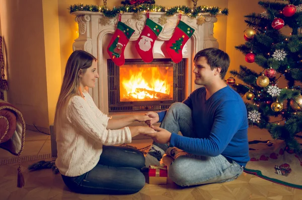 Feliz casal apaixonado sentado na lareira e de mãos dadas — Fotografia de Stock