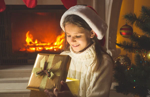 Getöntes Porträt eines lächelnden Mädchens, das am Kamin sitzt und — Stockfoto