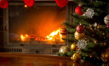 Yanında yanan şömine ile doğal bir şekilde dekore edilmiş Noel ağacı 