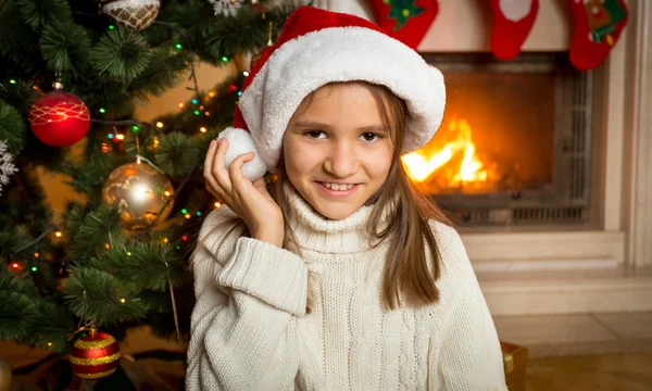 Portrait de fille de 10 ans dans le chapeau de Père Noël assis à côté du feu — Photo