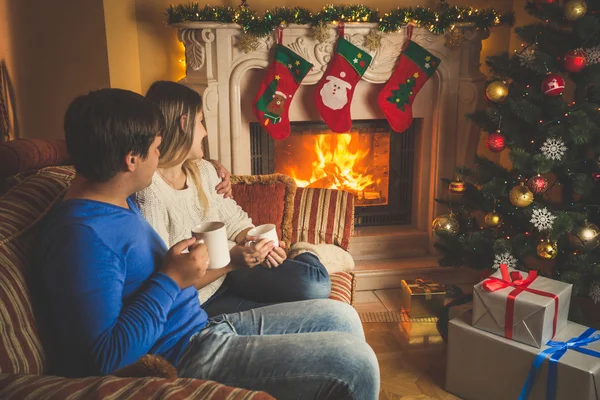 Mujer joven y hombre relajándose junto a la chimenea y decorado Chri —  Fotos de Stock